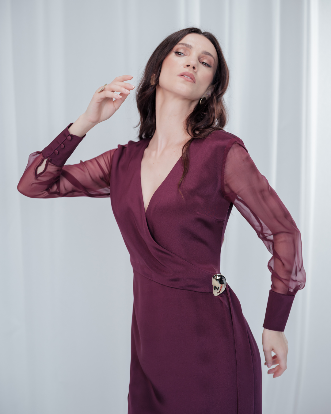 Amethyst Grace Dress in rich burgundy features a golden zamak accessory, sheer sleeves, and silk-covered buttons for opulent sophistication at formal events.