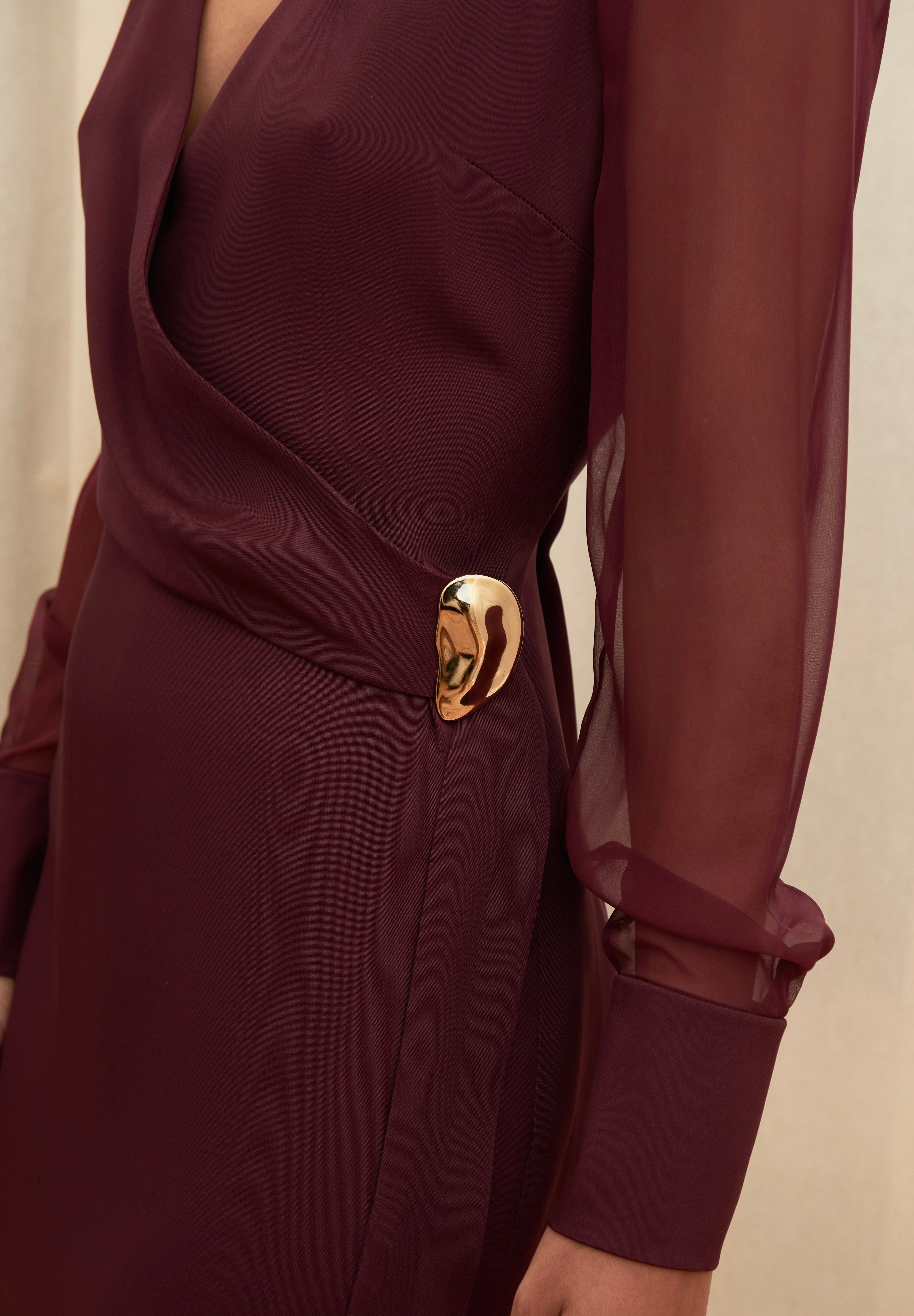 Amethyst Grace Dress in rich burgundy features a golden zamak accessory, sheer sleeves, and silk-covered buttons for opulent sophistication at formal events.