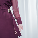 Amethyst Grace Dress in rich burgundy features a golden zamak accessory, sheer sleeves, and silk-covered buttons for opulent sophistication at formal events.