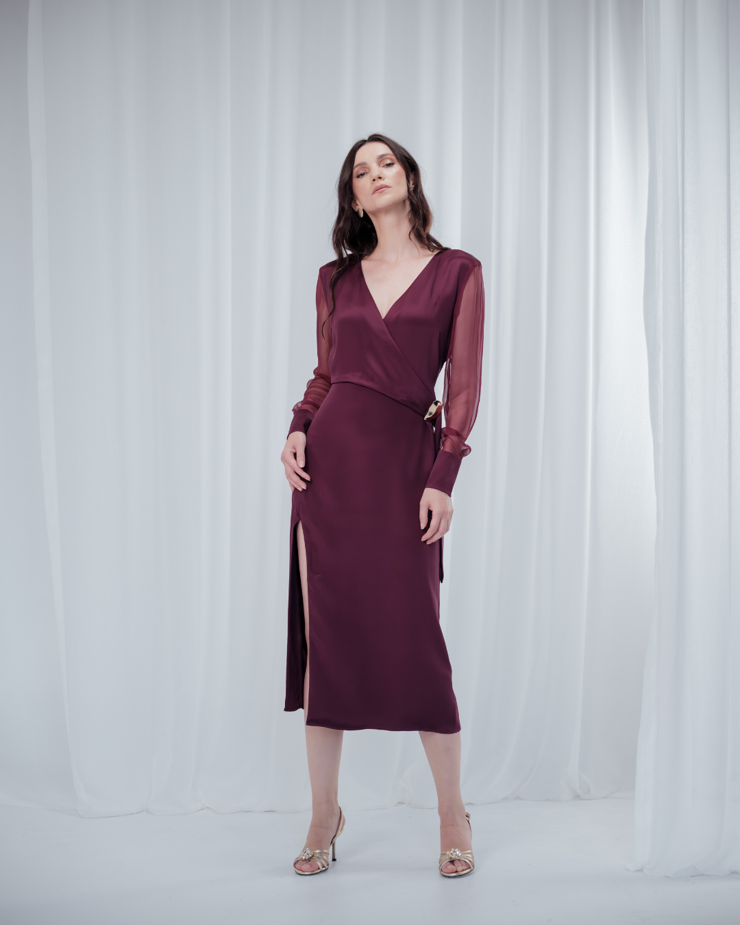 Amethyst Grace Dress in rich burgundy features a golden zamak accessory, sheer sleeves, and silk-covered buttons for opulent sophistication at formal events.