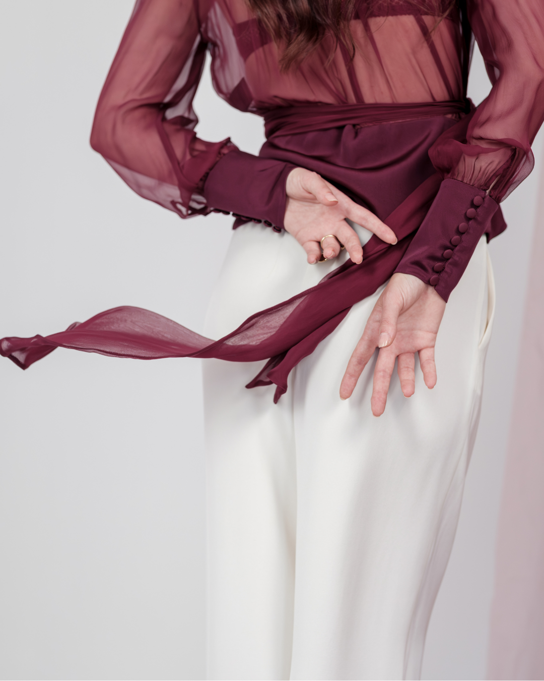 Berry Dusk Blouse in rich burgundy hue features a wrap design with silk-covered buttons and an adjustable waist tie - perfect for sophisticated day-to-evening wear.