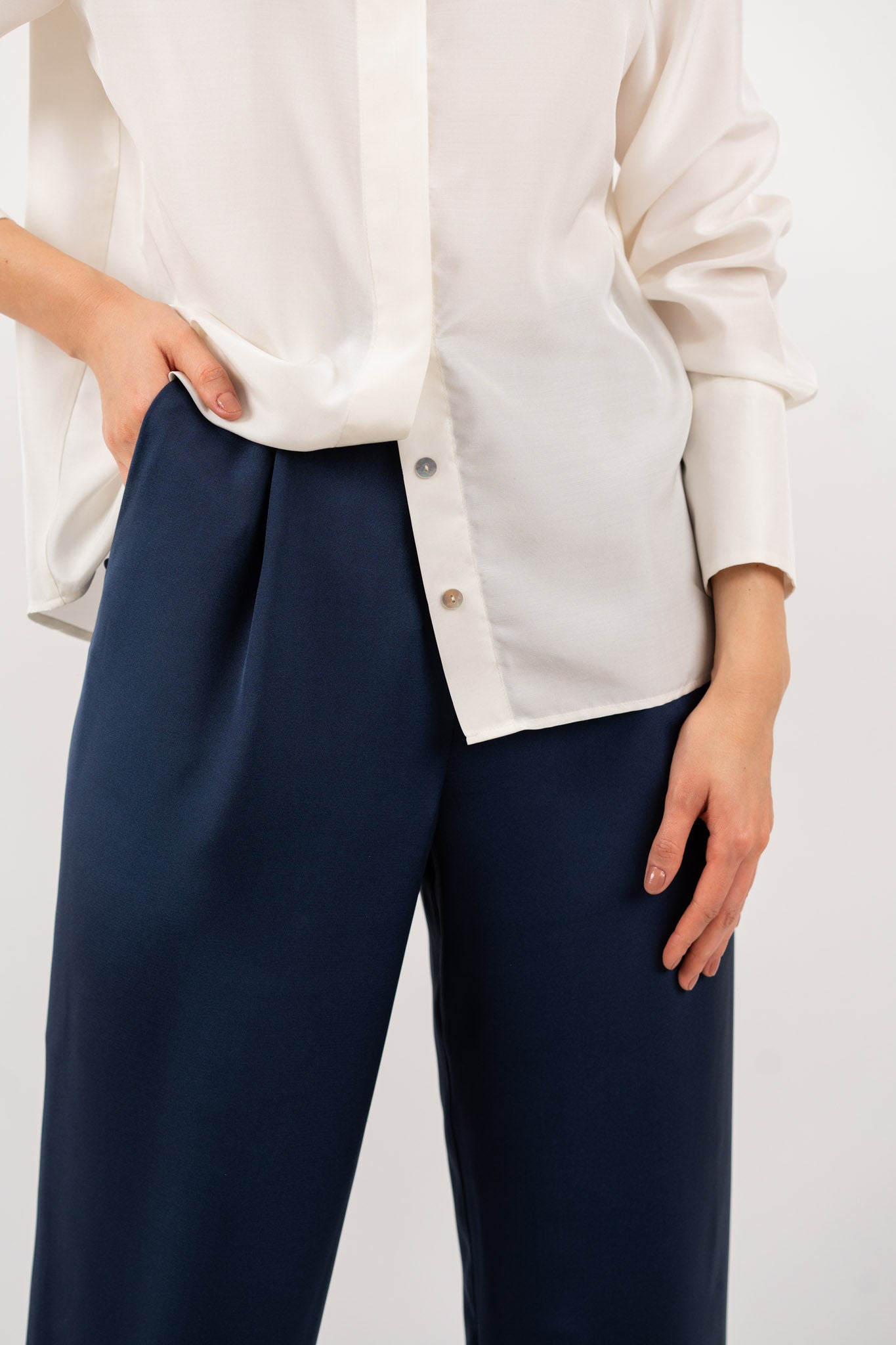 Close-up of navy blue tailored silk trousers, showcasing the soft sheen of silk blend fabric, impeccable stitching, and refined craftsmanship.
