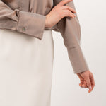 Close-up of bronze silk shirt, highlighting the soft, luminous silk fabric, delicate stitching, and elegant shell buttons.