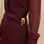 Amethyst Grace Dress in rich burgundy features a golden zamak accessory, sheer sleeves, and silk-covered buttons for opulent sophistication at formal events.