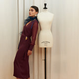 Amethyst Grace Dress in rich burgundy features a golden zamak accessory, sheer sleeves, and silk-covered buttons for opulent sophistication at formal events.