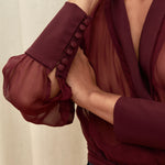 Berry Dusk Blouse in rich burgundy hue features a wrap design with silk-covered buttons and an adjustable waist tie - perfect for sophisticated day-to-evening wear.