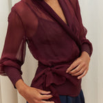 Berry Dusk Blouse in rich burgundy hue features a wrap design with silk-covered buttons and an adjustable waist tie - perfect for sophisticated day-to-evening wear.