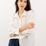 Close-up of ivory silk shirt, showcasing its soft silk texture, elegant shell buttons, and refined stitching.