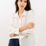 Close-up of ivory silk shirt, showcasing its soft silk texture, elegant shell buttons, and refined stitching.