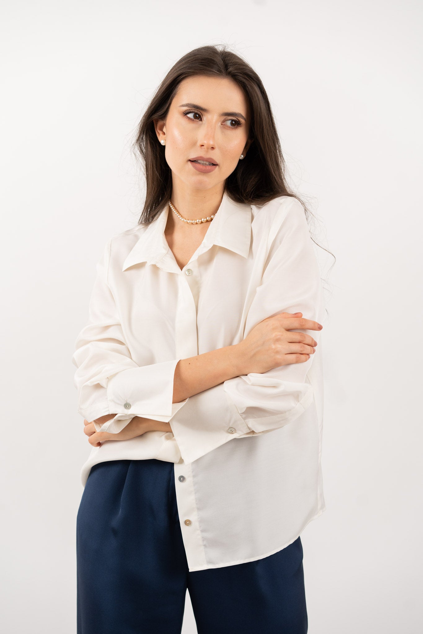 Close-up of ivory silk shirt, showcasing its soft silk texture, elegant shell buttons, and refined stitching.